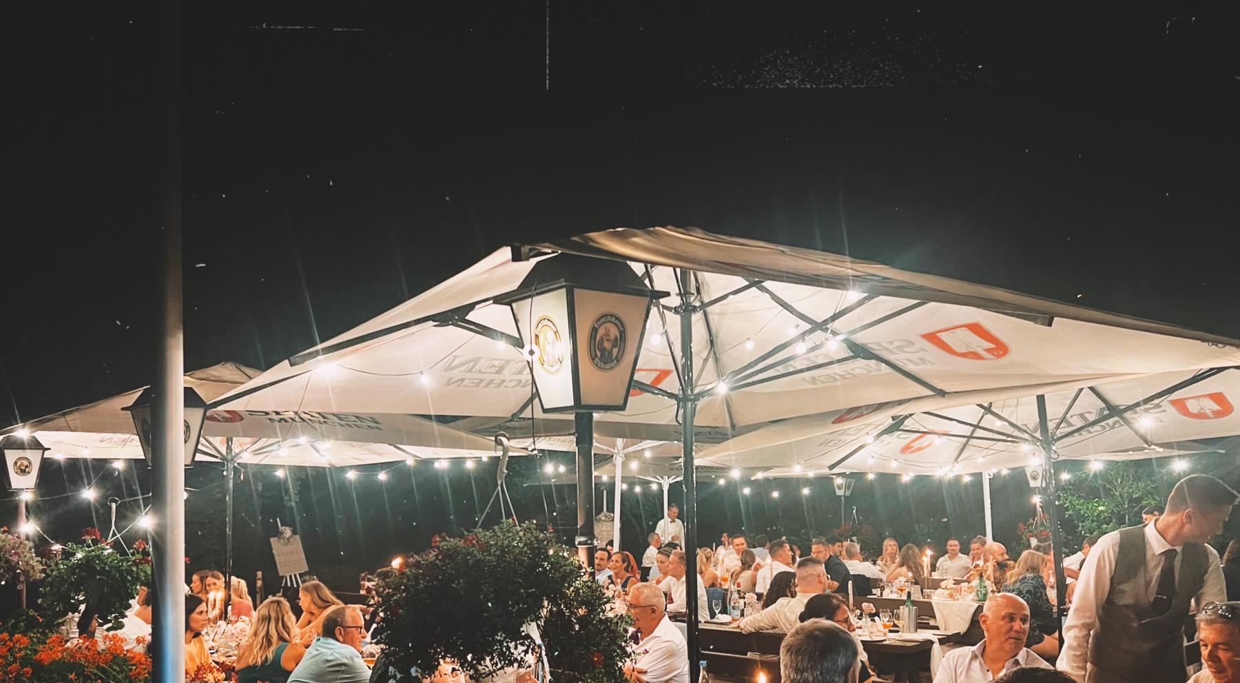 Biergarten am Abend mit Lichterketten unter den Schirmen